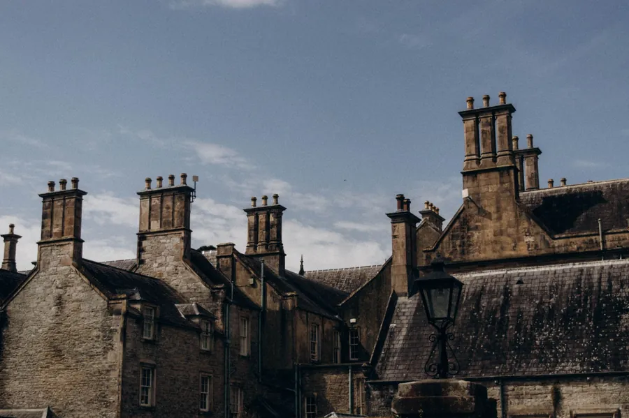 Old stone rooftops with multiple chimneys under a cloudy sky