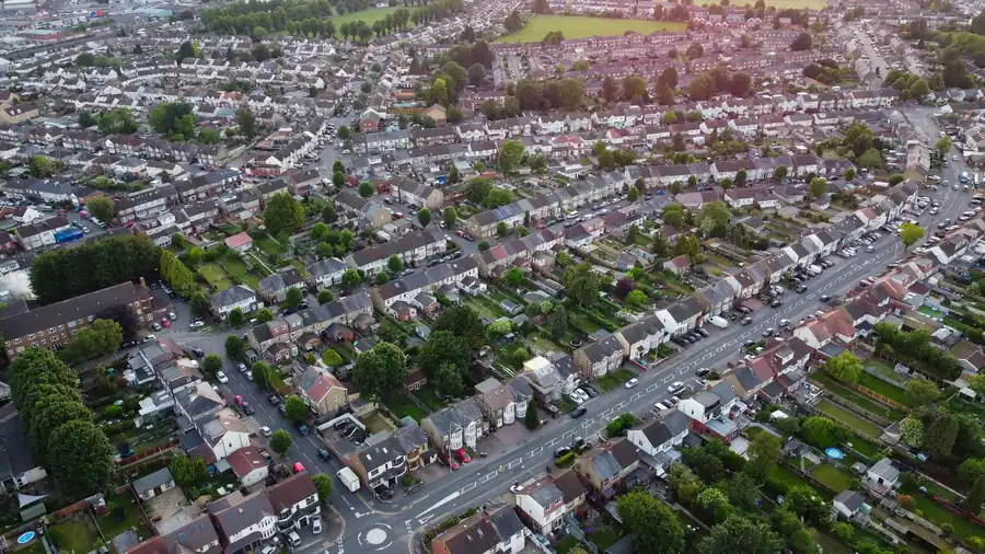 Aerial view of a suburban neighborhood with rows of houses, streets, and trees at sunset.