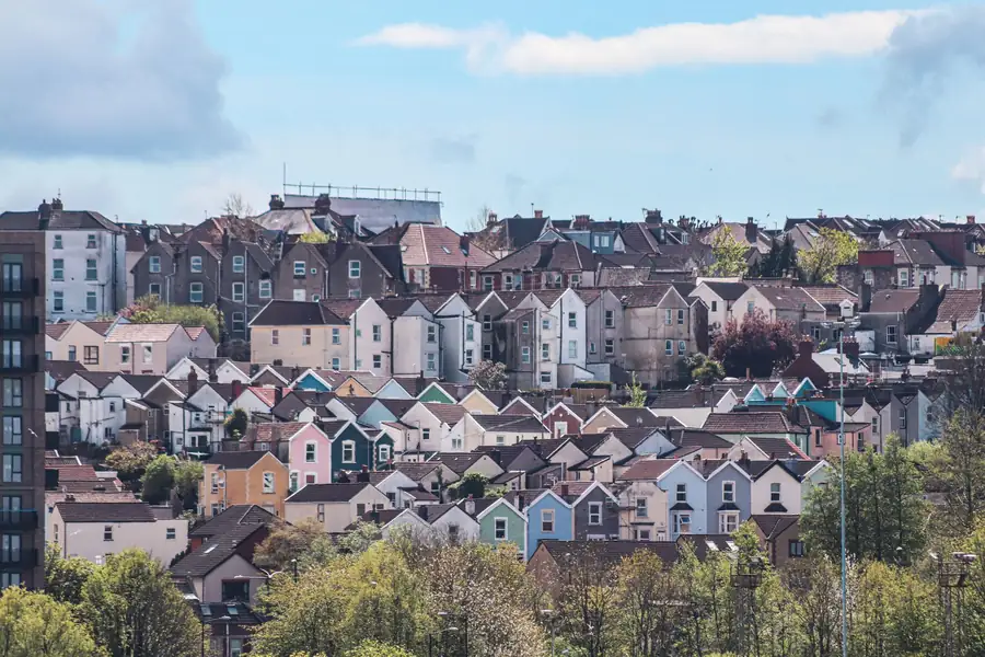 Colorful row of hillside houses beneath a blue sky, with trees in the foreground
