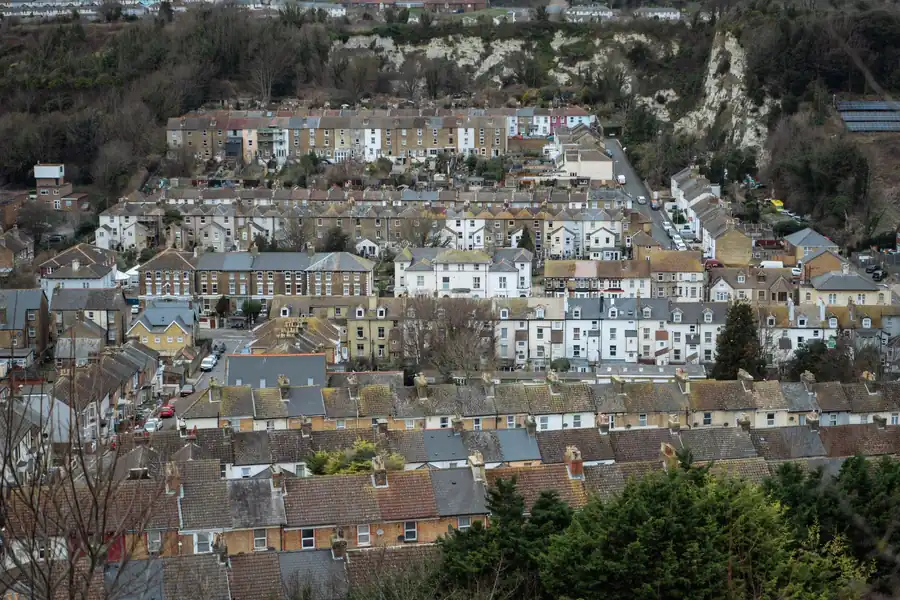 Hillside neighborhood with rows of houses and trees under an overcast sky