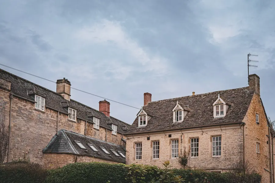 Stone courtyard buildings with slate roofs under a cloudy sky