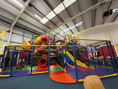 Indoor children’s play area with colorful slides, tunnels, and climbing nets under a high ceiling